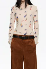 Camiseta de manga larga, corte ajustado, confeccionada en tul de poliamida con estampado de insectos y motivos florales en tonos azules, naranjas y verdes sobre fondo beige claro. Presenta cuello caja y puños con acabado en crudo.
