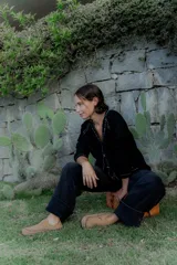 Saco tipo cardigan de punto color blanco con detalles de pespuntes decorativos en color negro a lo largo de los bordes y costuras. Presenta cuello en V, cierre frontal con botones y mangas largas.