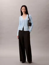 Cardigan de punto canalé con acabado brillante, cuello en V y cierre frontal con botones. Presenta un diseño de manga larga y corte ajustado.