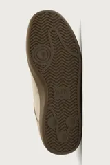 Zapatillas deportivas estilo retro de gamuza color tostado, con suela engomada marrón y detalle en tono amarillo en el talón.