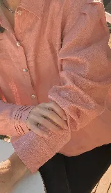 Camisa color rosa de lino, con cuello clásico, cierre frontal con botones y mangas largas con puños abotonados.