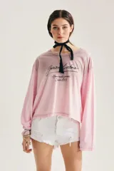 Remera oversize de manga larga color rosado con efecto degradé, cuello redondo amplio y estampado frontal con tipografía manuscrita.