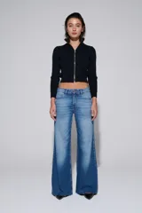 Pantalón de jean de tiro medio y pierna ancha, con lavado claro y zonas desgastadas.