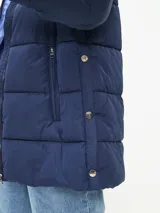 Campera puffer color blanco hueso, con cuello alto, cierre frontal con cremallera y bolsillos laterales con cierre.