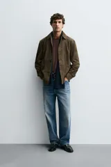 Sobrecamisa de corte relajado confeccionada en piel con acabado de ante. Presenta cuello solapa, cierre frontal con botones, mangas largas con puños abotonados y dos bolsillos delanteros de plastrón.