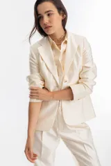 Blazer color crema confeccionado en tafeta, con cierre de un botón y mangas largas.