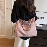 Bolso tipo tote color rosa, con doble asa corta color dorado y correa larga ajustable.