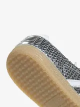 Championes Adidas Samba LT con acabado metálico plateado y textura de piel de serpiente. Presenta las icónicas tres tiras blancas en los laterales, suela de goma color caramelo y cierre de cordones.