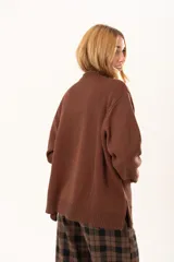 Buzo de punto color chocolate con diseño de flor grande en el frente en tonos rojos y centro texturizado en color crema. Presenta cuello redondo, mangas largas y puños y ruedo acanalados.