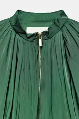 Cazadora satinada verde con cuello redondo fruncido y cierre frontal de cremallera metálica dorada. Presenta mangas largas abullonadas y diseño holgado.