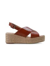Sandalia de plataforma con yute trenzado, tiras cruzadas de cuero marrón arrugado y tira ajustable al talón con hebilla metálica.