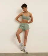 Bermuda deportiva tipo runner, color verde menta, confeccionada en microfibra con cintura elástica. Tiene un corte holgado y bajo redondeado.