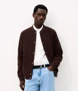 Campera bomber masculina de terciopelo cotelé color beige, con cuello redondo, mangas largas, cierre frontal de botones forrados, bolsillos laterales y terminaciones de elástico en puños y cintura.