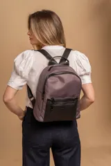 Mochila urbana de diseño combinado, confeccionada en tela resistente con bolsillo frontal y detalles en cuero sintético. Cuenta con compartimento principal con cierre y correas ajustables.