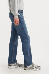 Jeans de corte regular fit en color azul medio, con diseño clásico de cinco bolsillos y cierre frontal con botón y cremallera.