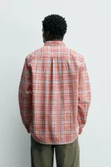 Camisa de manga larga relaxed fit a cuadros en tonos rosados, rojos y celestes. Cuenta con cuello abotonado, bolsillo de parche en el pecho y cierre frontal con botones.