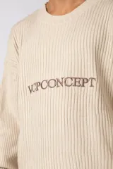 Sweater de tejido acanalado en color arena, con corte holgado y cuello redondo. Presenta el logo bordado VCPCONCEPT en el centro del pecho y una etiqueta pequeña en el puño.