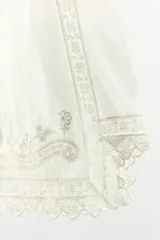 Bermuda de algodón blanca de tiro medio, con cintura elástica ajustable mediante cordón. Cuenta con delicados bordados florales y detalles de encaje a tono, con bajo acabado en ondas y aberturas laterales.