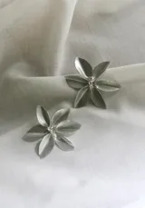 Par de aros plateados con forma de flor de cinco pétalos y centro con incrustaciones de strass.