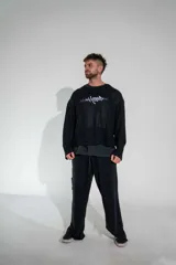 Buzo de tejido de punto fino en color negro, con diseño de cuello redondo y corte holgado. Presenta un estampado gráfico estilo gótico en el centro del pecho.