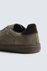 Zapatilla de estilo urbano confeccionada en piel con acabado de serraje en color marrón. Presenta cierre mediante cordones al tono, detalle de pespuntes en el empeine y suela de goma a tono.