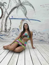 Conjunto de dos piezas tejido a crochet con diseño de bloques de colores. Incluye un top tipo crop con breteles finos y una pollera corta con cordón ajustable en la cintura con detalles de cuentas de madera.