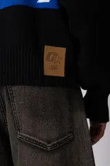 Campera tejida de punto con cierre frontal completo, cuello tipo polo y diseño con franja horizontal en contraste con estampado gráfico. Presenta puños y ruedo acanalados, con corte holgado.