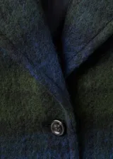 Abrigo de corte oversize con diseño de cuadros en tonos azul y verde. Presenta cuello con solapas, cierre frontal con botones, bolsillos laterales y manga larga.