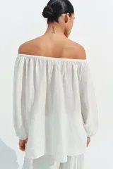 Blusa de lino color amarillo pastel, con escote recto ajustable mediante lazadas, hombros descubiertos y mangas largas abullonadas con puños elásticos.