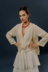 Chaqueta de lino color beige, de calce relajado, con escote en V, cierre frontal con botones y bolsillos frontales aplicados.