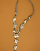 Collar artesanal compuesto por piezas irregulares de alpaca unidas por eslabones, con cordón de algodón natural regulable que permite ajustar el largo.