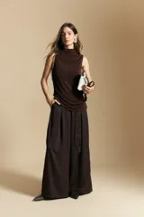 Top sin mangas de color negro con cuello alto y diseño drapeado en el frente. Confeccionado en una tela suave con acabado levemente satinado y silueta fluida.