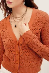 Cardigan cropped de punto calado color tostado, con escote en V, manga larga y cierre frontal con botones.