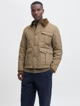 Campera acolchada de diseño matelasse en color tostado, con cuello camisero en pana marrón, cierre frontal con broches a presión, bolsillos frontales con solapa y puños ajustables.