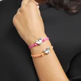 Pulsera elástica de hilo naranja con un dije central de corazón plateado y un cierre esférico plateado.