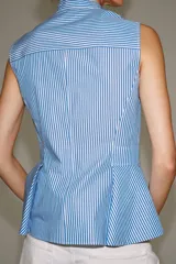 Camisa sin mangas de algodón con rayas verticales blancas y azules, cuello mao, bajo acabado en peplum y cierre frontal con alamares decorativos de nudo.