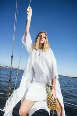 Camisa larga de silueta amplia y fluida, color blanco, con mangas anchas tipo kimono, cuello cerrado y abertura frontal parcial.