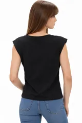 Remera de algodón blanca, de corte holgado y sin mangas, con cuello a la base y detalle de ojalillos metálicos sobre los hombros.