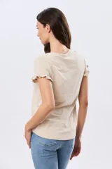 Remera de algodón color verde menta, con escote redondo y mangas corta con detalles de volados sutiles en los puños.