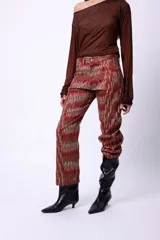 Pantalón de corte recto y largo al tobillo, con estampado de espiga en tonos oscuros y líneas rojas. Presenta tiro medio y cierre frontal.