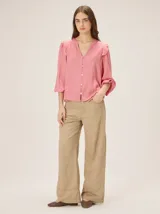 Pantalón de tiro medio-alto, corte recto y amplitud en las piernas, color tostado, con bolsillos delanteros y traseros y detalles de costuras y cortes pespuntados.