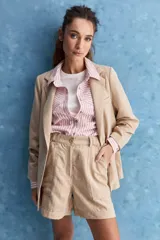 Short de tiro alto en color beige, con diseño de silueta relajada, bolsillos delanteros aplicados de gran tamaño y bolsillos traseros. Cuenta con cintura con presillas y cierre frontal.