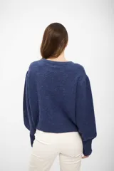 Buzo de tejido de punto azul oscuro con cuello redondo y un diseño lineal de una flor en blanco en el frente.