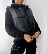 Chaleco puffer negro con cuello alto y cierre frontal con cremallera. Tiene bolsillos laterales y diseño acolchado.