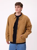 Campera de lona color tostado con cierre frontal, cuello camisero y bolsillo en el pecho. Presenta un diseño de estilo workwear con interior forrado.