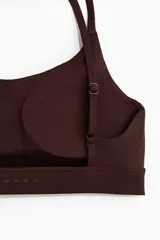 Top deportivo SculptMove color marrón, con escote redondo, breteles finos cruzados en la espalda y bajo elástico. Cuenta con copas forradas con relleno extraíble.