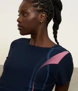 Remera deportiva de manga corta color azul marino con diseño de ondas y detalles estampados en tonos rosados y celestes. Confeccionada en microfibra de poliéster y elastano, de secado rápido y corte entallado.
