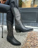 Botas texanas de caña alta confeccionadas en cuero negro, con costuras decorativas en contraste color ocre en la caña y taco cuadrado de madera.