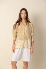 Camisa de corte holgado con estampado floral en tonos amarillos y lilas, cuello clásico y cierre frontal con botones.