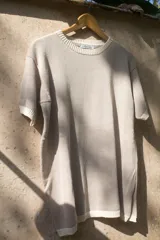 T-shirt de tejido artesanal color rojo intenso, con cuello redondo y bordes en color marrón. Presenta mangas cortas y un calce holgado.